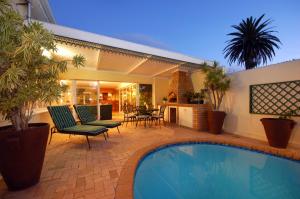 a patio with a pool and chairs and a house at Anchorage Guesthouse in Port Elizabeth