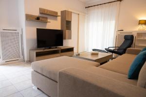ein Wohnzimmer mit einem Sofa und einem Flachbild-TV in der Unterkunft Spacious apartment close to the sea and the city center in Athen