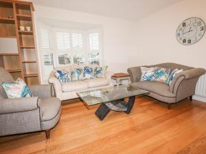 a living room with two couches and a glass table at 1 Old Talbot Cottages in Lostwithiel
