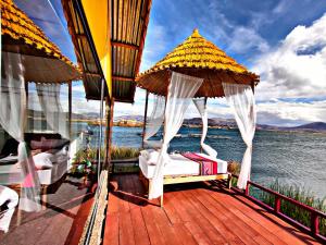 eine Terrasse mit Stühlen und Sonnenschirmen auf dem Wasser in der Unterkunft Uros Qhantany Lodge in Puno