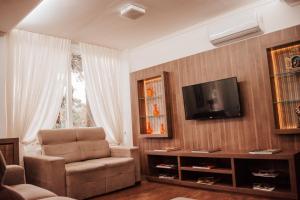 ein Wohnzimmer mit einem Stuhl und einem TV in der Unterkunft Hotel Colina São Francisco in Gramado