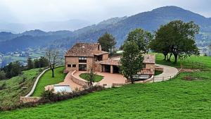 an old house on a hill in a green field at El Guitart in Ripoll