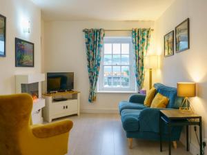 a living room with a blue couch and a window at Pass The Keys Modern 2 bed flat overlooking Aberaeron Harbour in Aberaeron