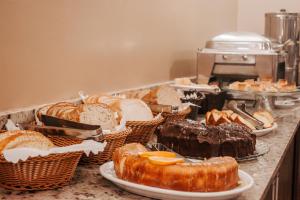 a bunch of different types of bread and pastries on a counter at Hotel Colina São Francisco in Gramado