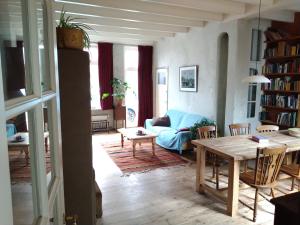 een woonkamer met een tafel en een blauwe bank bij Logies de Zeeuwse Klei, een gezellig jaren 30 huis in Middelburg
