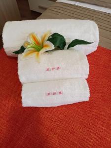 three towels with a flower on top of a table at La Petite Maison in Aci Castello