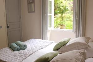 een bed met kussens in een kamer met een raam bij Mas de Rique in Saint-Étienne-du-Grès