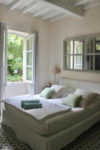 een slaapkamer met een groot wit bed met een raam bij Mas de Rique in Saint-Étienne-du-Grès