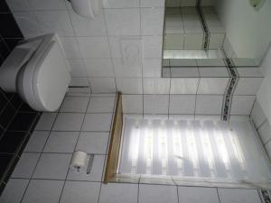 ein weiß gefliestes Bad mit einem WC und einem Fenster in der Unterkunft Ferienwohnung Litterscheid in Kiefersfelden