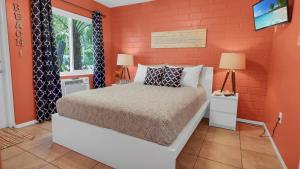 1 dormitorio con cama y pared roja en The Beach House - Treasure Island, en St Pete Beach