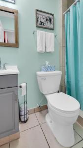 a bathroom with a white toilet and a blue shower curtain at The Beach House - Treasure Island in St Pete Beach