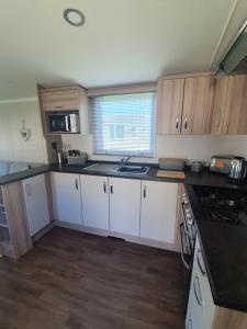 uma pequena cozinha com armários brancos e um lavatório em Seton Sands Holiday Home em Port Seton