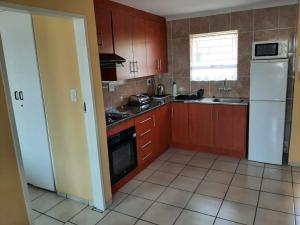 a kitchen with wooden cabinets and a white refrigerator at TM Self Catering Accommodation in Middelburg