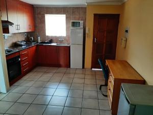 a kitchen with red cabinets and a white refrigerator at TM Self Catering Accommodation in Middelburg