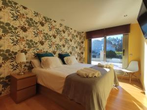 um quarto com uma cama com lençóis brancos e papel de parede floral em Sanxenxo Casa Rial 47 con PISCINA CLIMATIZADA em Sanxenxo