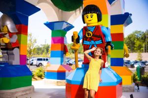 una niñita parada junto a una estatua de lego en LEGOLAND New York Resort, en Goshen