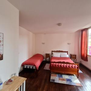 um quarto com 2 camas e lençóis vermelhos em LE COMMERCE em Pont-sur-Yonne