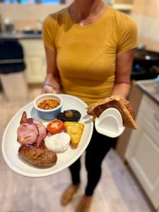 a woman holding a plate of breakfast food at Lacet House in Ambleside