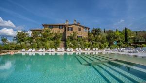 a large swimming pool with chairs and a house at Il Poggio degli Olivi in Bettona