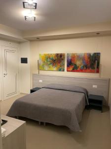 Nemoli的住宿－Alba Relais，卧室配有一张床,墙上挂有两幅画