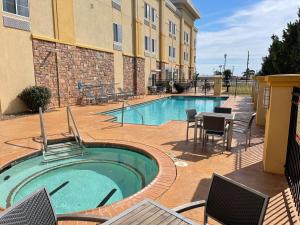 a pool with chairs and a table next to a building at La Quinta by Wyndham Elk City in Elk City