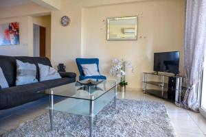 ein Wohnzimmer mit einem Sofa, einem Tisch und einem TV in der Unterkunft Melania Gardens Apartment in Klorakas
