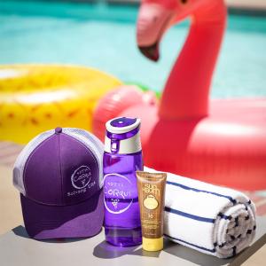 a bottle of sunscreen and a hat and a towel at Hotel Corque in Solvang