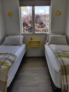 two beds in a room with a window at Mývatn apartments in Myvatn