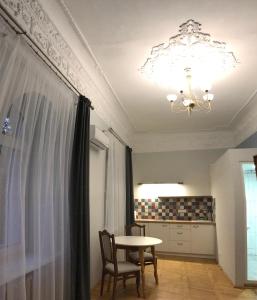 ein Esszimmer mit einem Tisch und einem Kronleuchter in der Unterkunft Ermitage Apt, Апартаменти в Центрі Дніпра in Dnipro