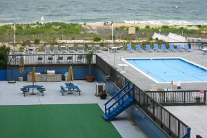 a swimming pool with tables and chairs and the ocean at Fountainhead Towers in Ocean City +11 photos