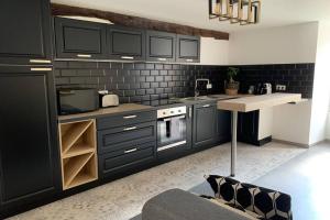 uma cozinha com armários pretos, um lavatório e um balcão em Belle-Vue em Hautvillers