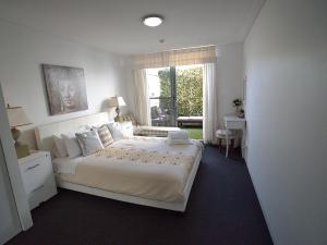a white bedroom with a large bed and a window at Blue Coral Terrace Coast Luxury 31 in The Entrance