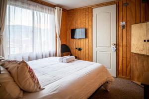 een slaapkamer met een groot bed en een raam bij Hostal Lejana Patagonia in Cochrane