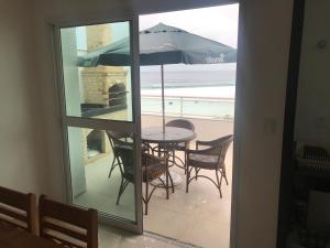 Un patio con una mesa y sillas y una sombrilla. en Cobertura Arraial do Cabo Frente, en Arraial do Cabo