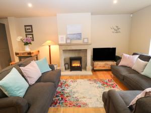 a living room with two couches and a fireplace at 1 Stansfield Mews in Keighley