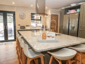a kitchen with a large island with white bar stools at 1 Stansfield Mews in Keighley