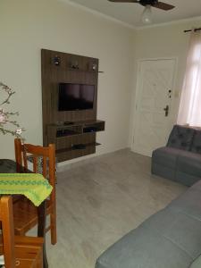 a living room with a couch and a flat screen tv at Apartamento 2 qtos Praia de Santos in Santos