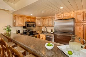a kitchen with wooden cabinets and a stainless steel refrigerator at Standard Two Bedroom - Aspen Alps #106 in Aspen