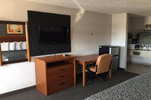 una camera d'albergo con scrivania, TV e letto di Hebbronville Executive Inn a Hebbronville
