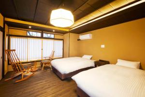 a room with two beds and a table and chairs at Rinn Shijo Takase River North in Kyoto