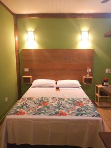 a bedroom with a large bed with a floral bedspread at Chalé de Charme Mandomai in Ilhabela