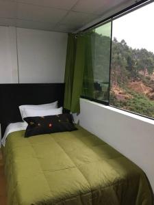 a bedroom with a green bed and a window at Panoramic independent apartment-Regen Wasi in Cusco