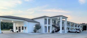 un gran edificio blanco con un coche aparcado en un aparcamiento en Rodeway Inn Sandersville, en Sandersville