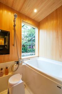 a bathroom with a tub and a window and a toilet at Rinn Shijo Takase River North in Kyoto