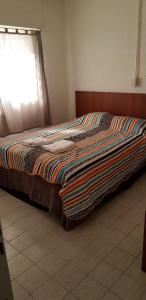 una cama con una colcha colorida en un dormitorio en Rio Grande, en Neuquén 5 fotos más