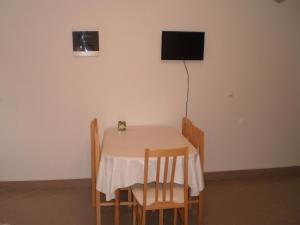 uma mesa com cadeiras e uma televisão na parede em Apartments GUNJA em Poljica
