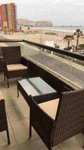 a balcony with chairs and a table and a view of the beach at Departamento por día ARICA in Arica