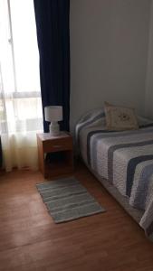 a bedroom with a bed and a table with a lamp at Departamento por día ARICA in Arica