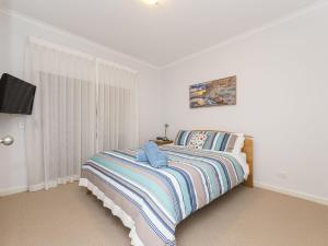 a white bedroom with a bed and a tv at The Sails 8 in Inverloch