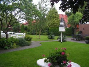 einen Garten mit einem Vogelhaus und einem Tisch mit Blumen in der Unterkunft B&B Berkenrode in Rockanje